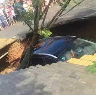 路面塌陷小车坠坑后却围满戴孝人?